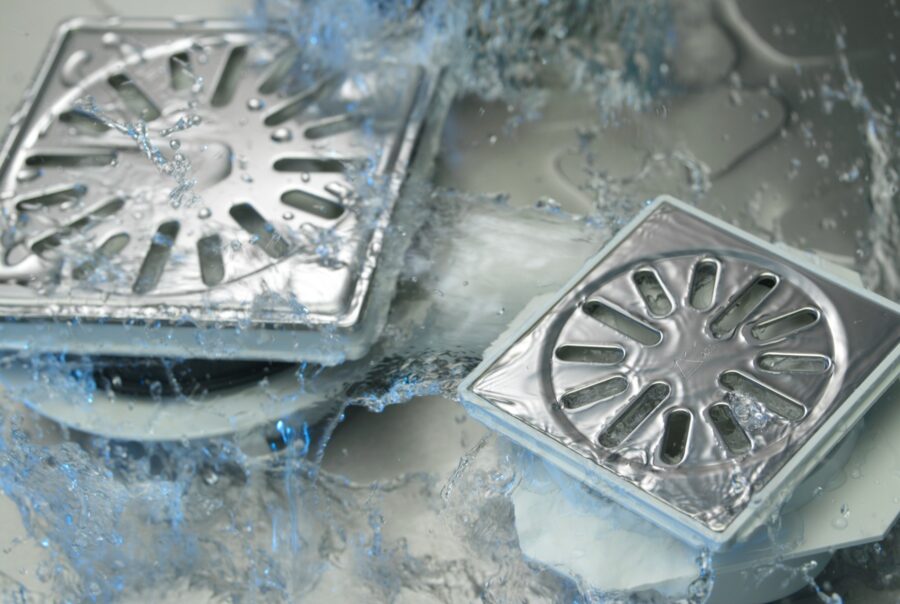 Sfeerbeeld van rvs afvoerput roosters met stromend water dat er doorheen stroomt.